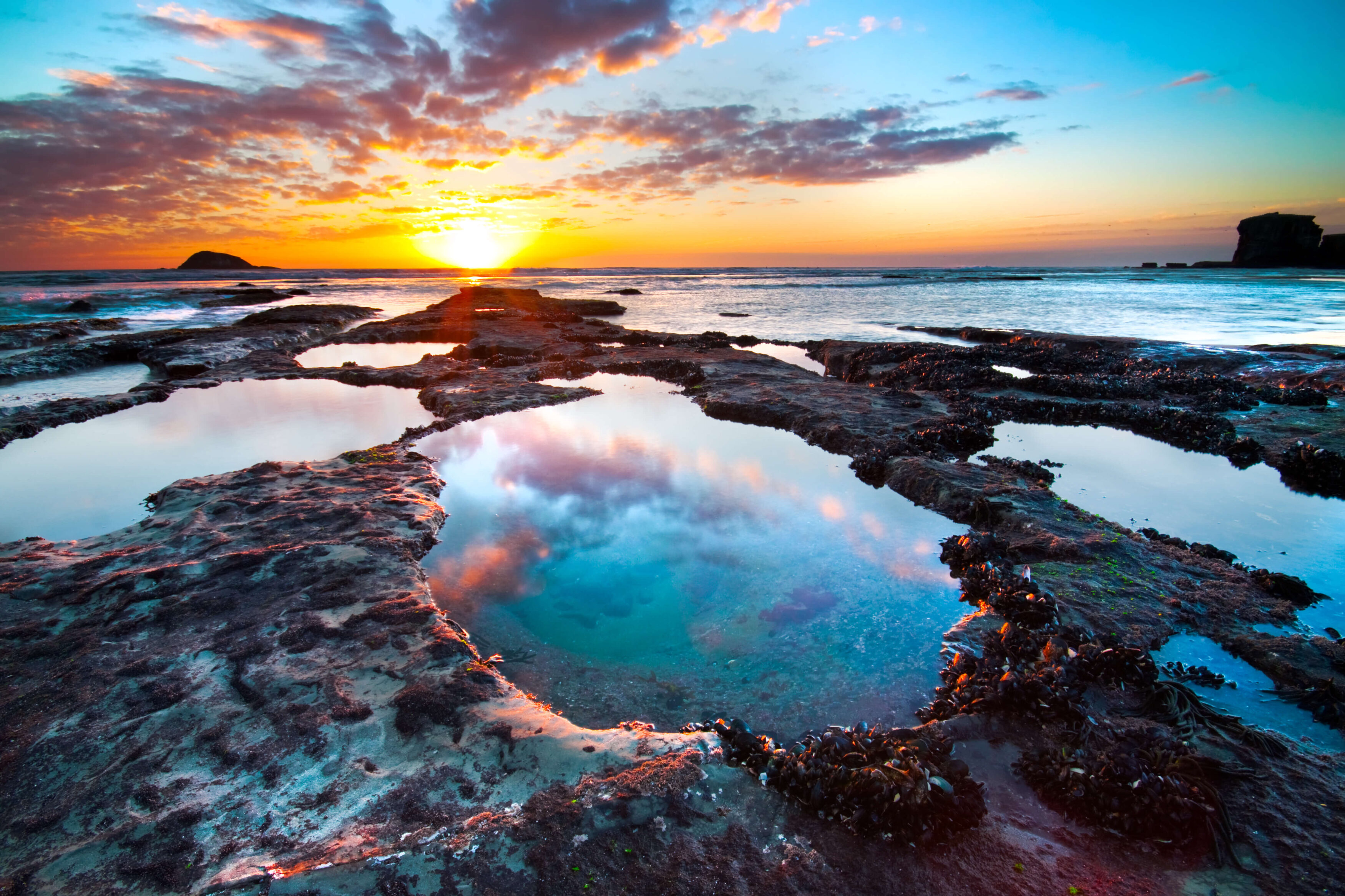 An image of the sunset and the clouds reflected on the ocean life